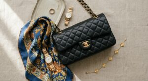 A high-end editorial flat-lay featuring a curated selection of five timeless fashion accessories, in