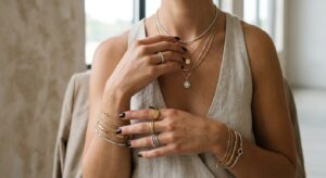 Close-up editorial shot of a woman's hands and neckline elegantly wearing a curated mix of layered g